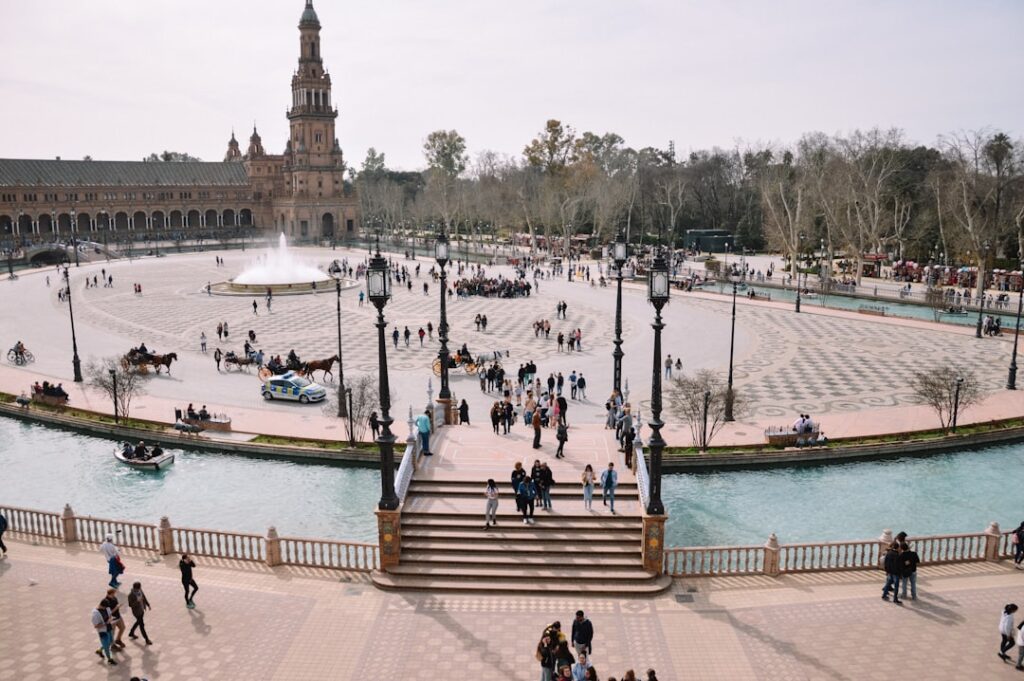 a group of people walking around a plaza next to a fountain