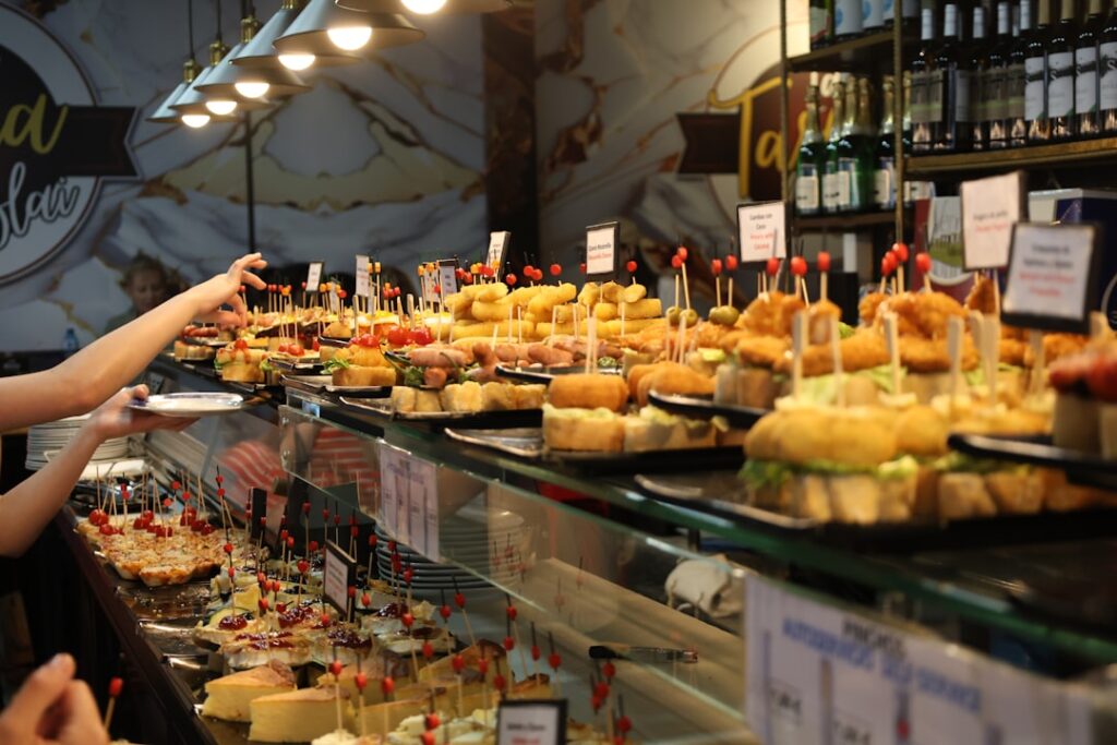 A bar counter filled with numerous pintxos and people.