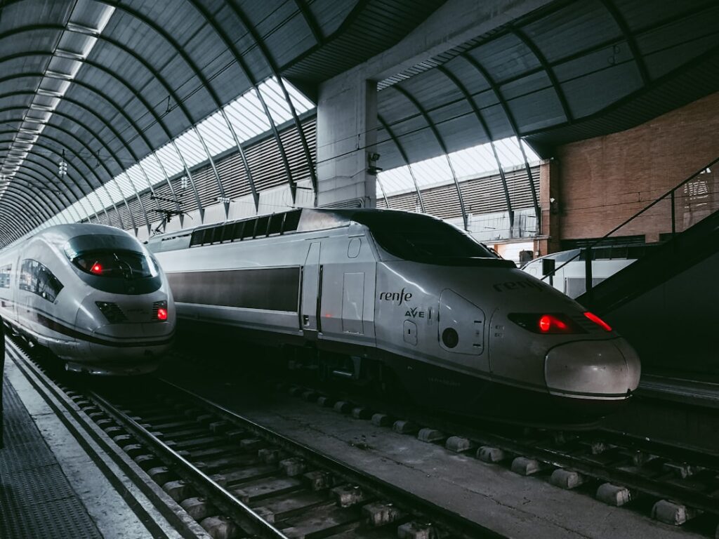 a silver train traveling down train tracks next to a loading platform