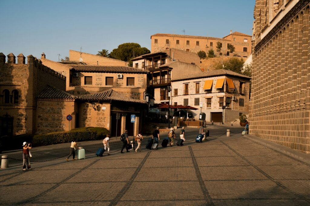 A group of people walking with suitcases on a cobblestone street in Toledo